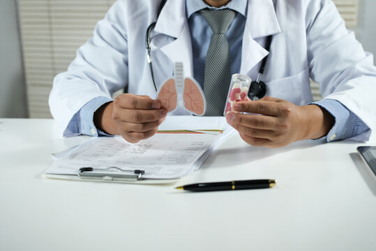 A doctor holds a lung model with medicine bottles in a clinic. Lung cancer, asthma, chronic obstructive pulmonary disease (COPD), bronchitis, emphysema, and cystic fibrosis. Treatment and care for lun