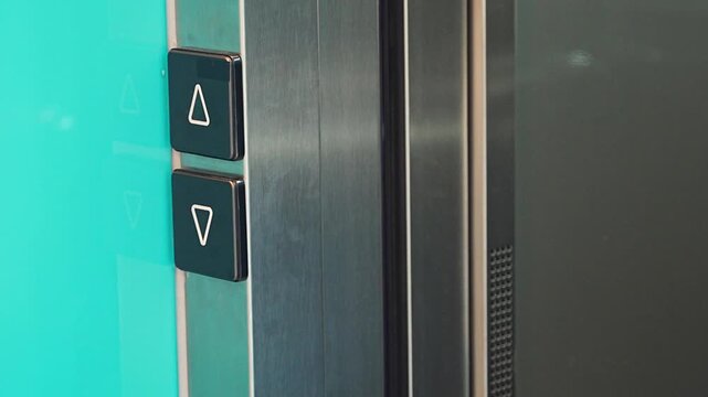 Close up of elevator call button as a person exits the lift. Everyday elevator access supports efficient movement and convenient residential living