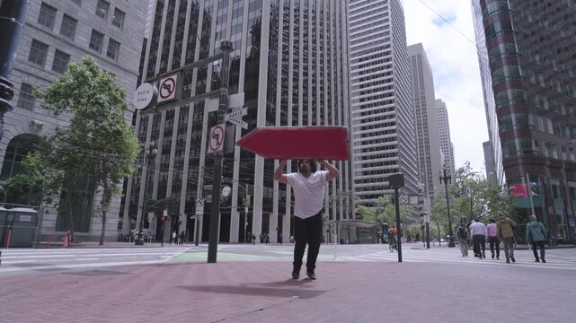 Man Spinning Painted Board Overhead In Downtown San Francisco Intersection, Low Wide Shot