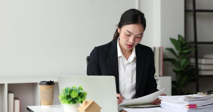 Professional businesswoman organizing a large stack of documents, highlighting a busy office workload