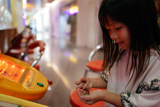 cute little Asian girl playing pinball machine