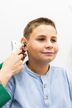 Vertical photograph of a child undergoing a hearing test with a digital otoscope at a medical center. Concept of hearing problem prevention in young children.