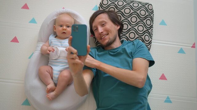 Father video calling family beside baby in soft baby nest.