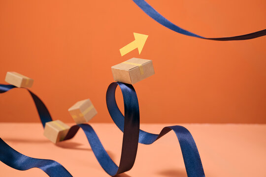 Small cardboard boxes balanced on a flowing navy blue ribbon
