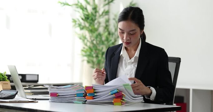 Professional businesswoman organizing a large stack of documents, highlighting a busy office workload