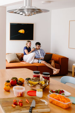 A smiling couple relaxes on a sofa while watching a laptop.