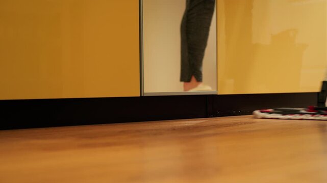 Housewife cleaning the wooden parquet kitchen floor with a mop