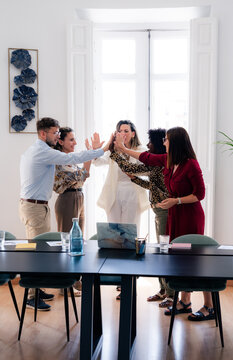 Work Team Celebrates Success in Office Meeting Room With High-Fives