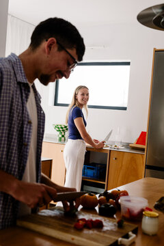 A blonde woman and a man prep food in a bright, modern kitchen.