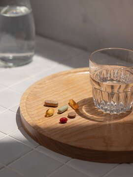 Various vitamin pills and supplements scattered on a wooden tray