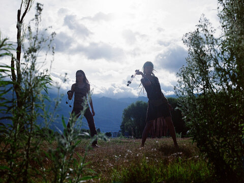 Fire Dancers with Poi Rings in a Field at Dusk