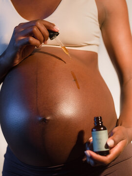 Woman applying anti stretch mark serum on belly 