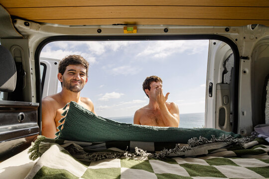 Friends getting ready for surfing at campervan coastal stop