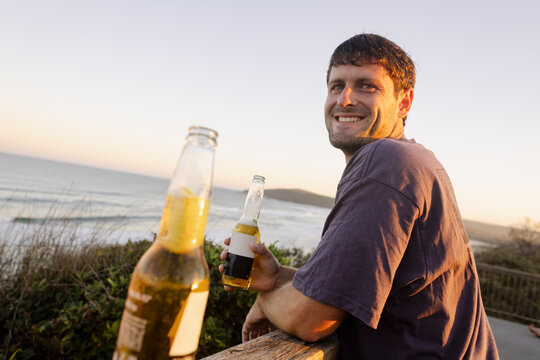 Friend drinking beer by the ocean at sunset in Angourie Point