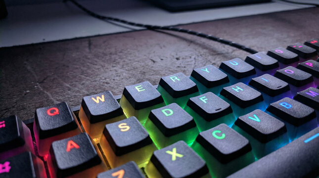Mechanical Keyboard RGB Lighting Gaming Setup Close Up. Macro shot of mechanical keyboard keys with rainbow RGB backlighting, dark moody atmosphere, gamer aesthetic