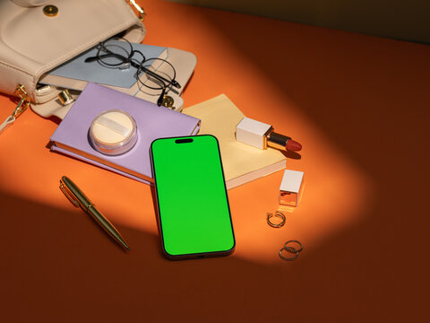 Stylish woman's everyday essentials laid out with a green screen phone