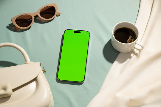 Stylish flat lay with a smartphone, sunglasses, handbag, and coffee