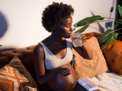 Pregnant woman drinking water and taking vitamins 