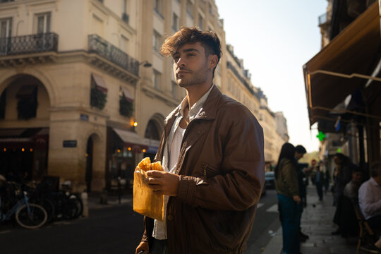 Man holding a fresh croissant on a Paris street corner