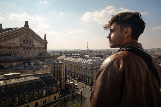Man looking at the Paris cityscape and Eiffel Tower from a rooftop