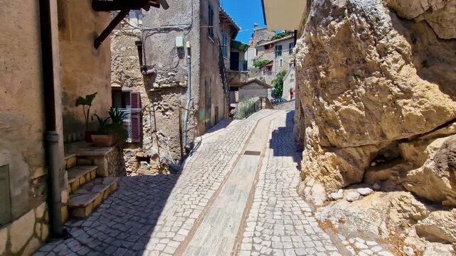 authentic Roccantica Italy 4K. POV walk through stone arch entrance into medieval hilltop borgo village street. Cinematic walking tour revealing ancient stairways and colorful flower pots video asset