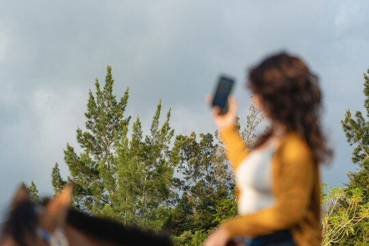 Woman taking selfie outdoors with smartphone against trees
