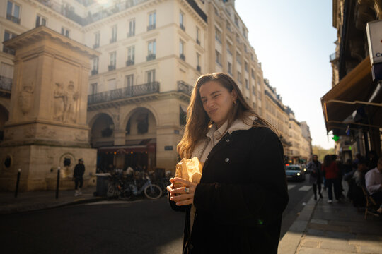 Young woman with a pastry on a Parisian street corner