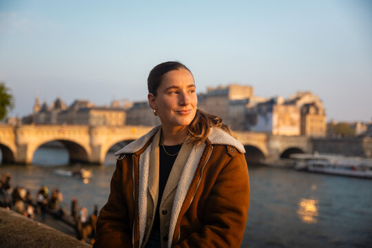 Smiling woman by the Seine River at golden hour