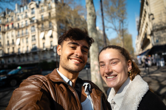 Happy travelers posing together on sunny Paris street