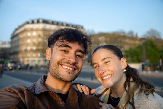Happy couple smiling for a selfie on a sunny day in Paris