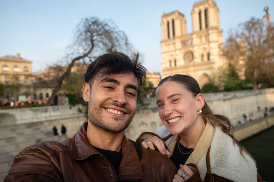 Happy young couple taking a selfie in front of Notre-Dame Cathedral