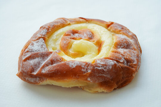 Traditional Mallorcan ensaimada pastry filled with custard cream, close-up on white background 