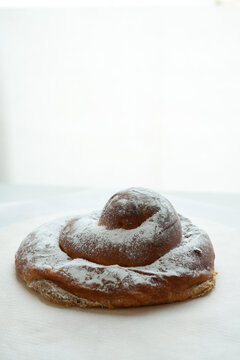 Delicious traditional Spanish ensaimada bun with icing sugar for breakfast with copy space 