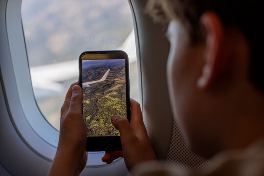 Boy is filming the landscape in an airplane 