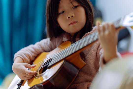 Young Girl Plays Guitar During Music Practice at Home