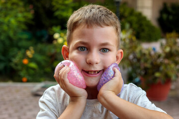 Smiling little boy playing with a glittery dumpling shaped squishy toy outdoors, squeezing a colorful sensory stress relief toy during fun playtime in the garden © Татьяна Швец