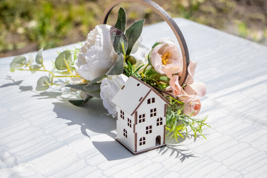 Decorative wooden house with floral arrangement on white tablecloth