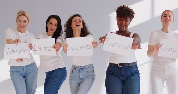 Happy multi ethnic group of successful confident women holding motivational quotes, female team leaders holding inspiring statements, drive for success positive phrases to improve girl life, support
