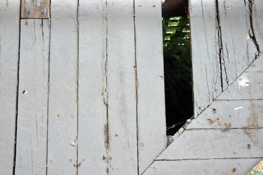 Close up abstract view of an old broken wooden privacy fence with a visible gap hole exposing structural damage needing home improvement carpenter repair work.