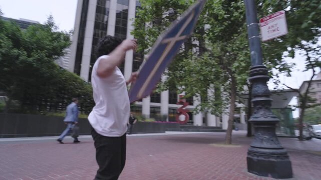 Happy Man Swinging Blue Cross Board Around In San Francisco Plaza - Steady Cam Around