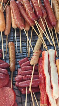 Assorted Asian street food skewers including sausage, fishballs and crab sticks on a grill