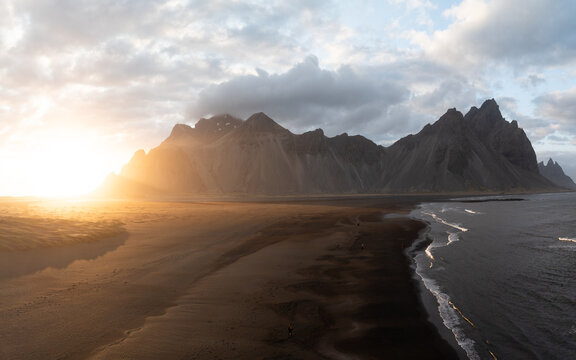 Aerial view of Stokksnes and the dramatic Vestrahorn mountain rising above the black sand beach at sunset in Iceland.