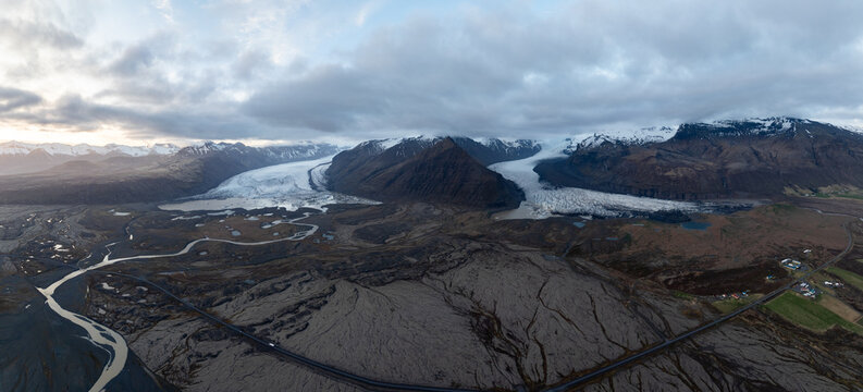 Aerial view of Svinafellsjokull glacier with its massive ice tongues, rugged mountain peaks, and winding glacial rivers flowing through the volcanic landscape in Sveitarfelagid Hornafjordur, Iceland.
