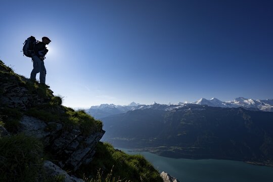 Mountain ridge with mountaineers and Swiss mountains and Lake Thun in the background at sunrise, Interlaken, Bernese Oberland, Switzerland