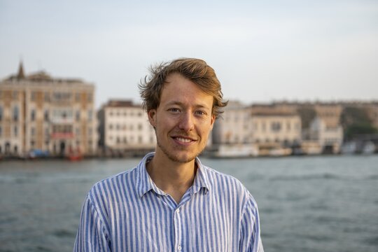 Young man in striped shirt, portrait, on the banks of the Grand Canal, looking into the camera, Venice, Veneto, Italy