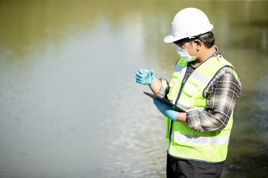 Environmental scientist testing water quality using a flask and tablet at the shoreline in a serene natural environment