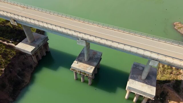 4K aerial footage of a concrete bridge crossing green reservoir water