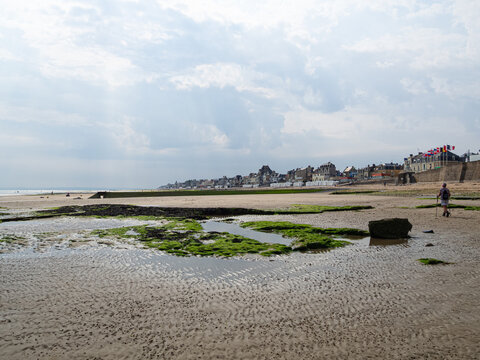 Playa de Saint-Aubin-sur-Mer, vista del paisaje de nubes y mar sobre arena dorada con algas verdes, viajando en verano de 2022