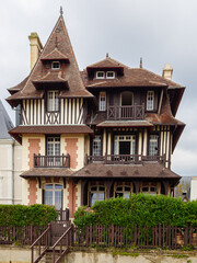 Vista de la fachada de casas lujosas con tejados puntiagudos y entramado de madera en la fachada en la Playa de Trouville-sur-Mer, viajando por la Normandía francesa en verano 2022 © acaballero67