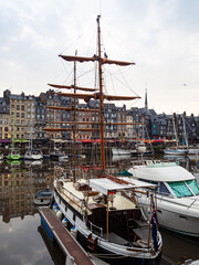 Vistas pintorescas del puerto de Honfleur, con barcos amarrados, veleros y edificios de colores reflejados en el agua, viajando por la Normandía de Francia en verano de 2022 © acaballero67